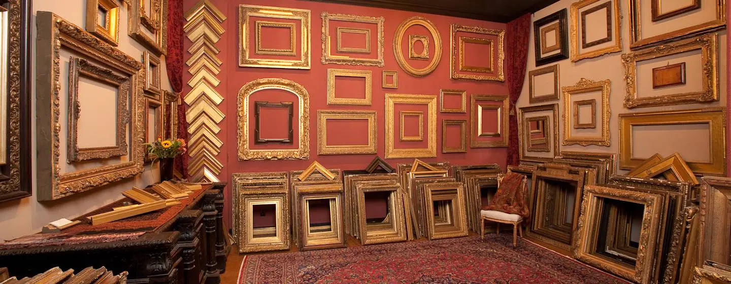 A room filled with lots of gold frames on the wall.