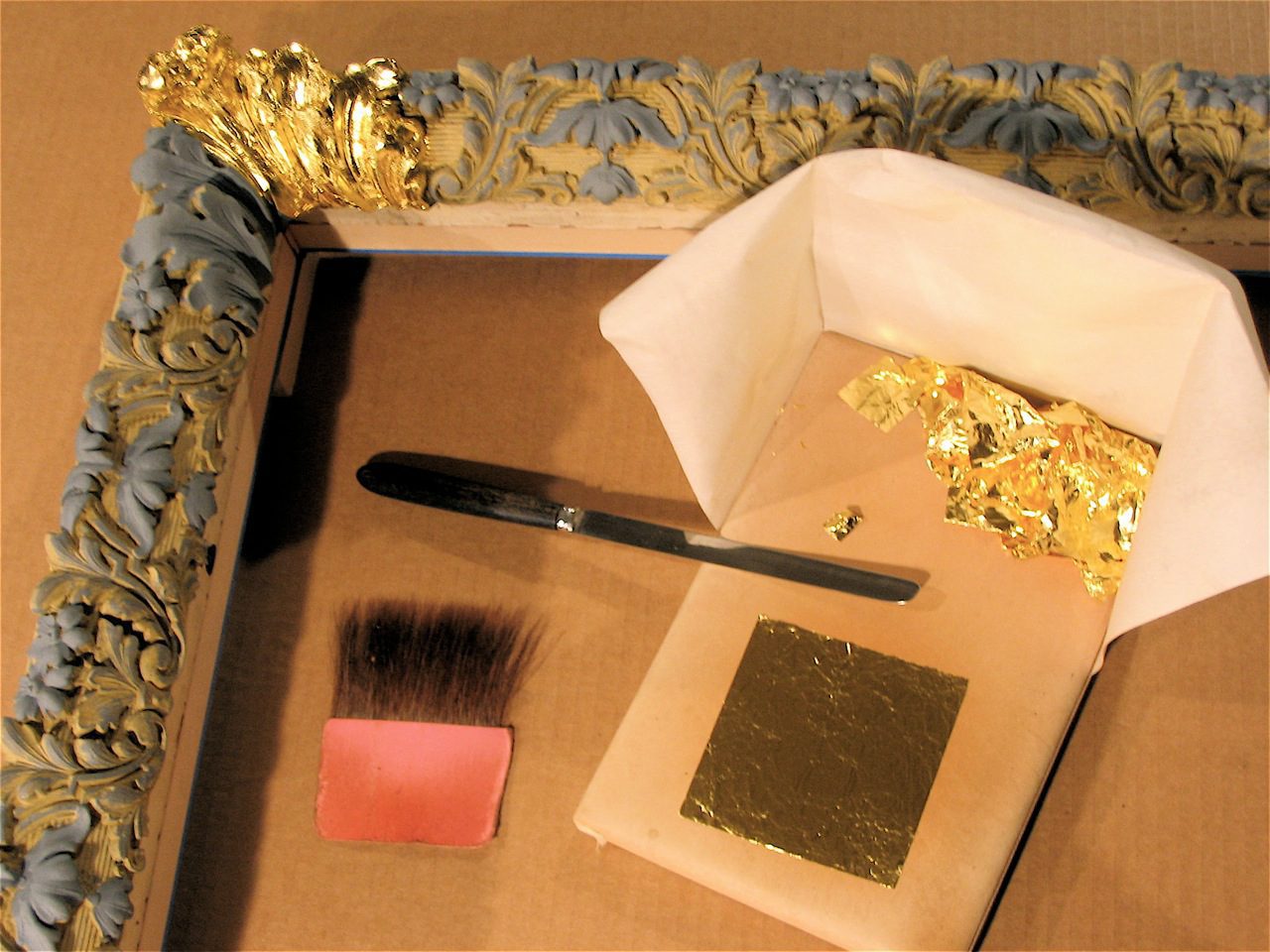 A box with some gold leaf and a brush