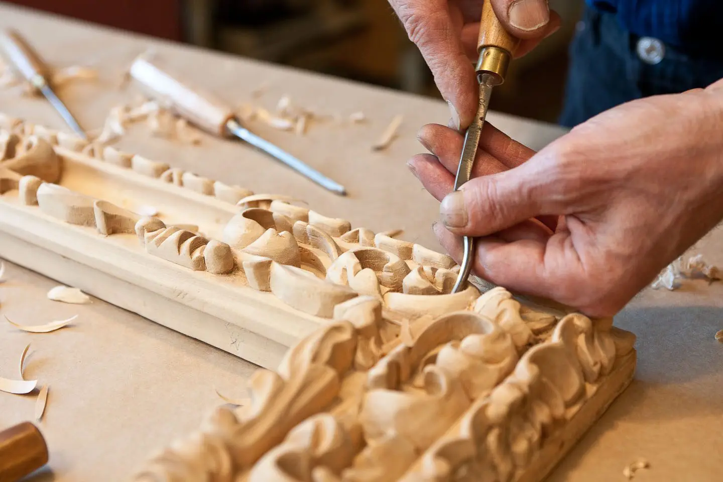 A person carving wood with a knife and a pair of scissors.