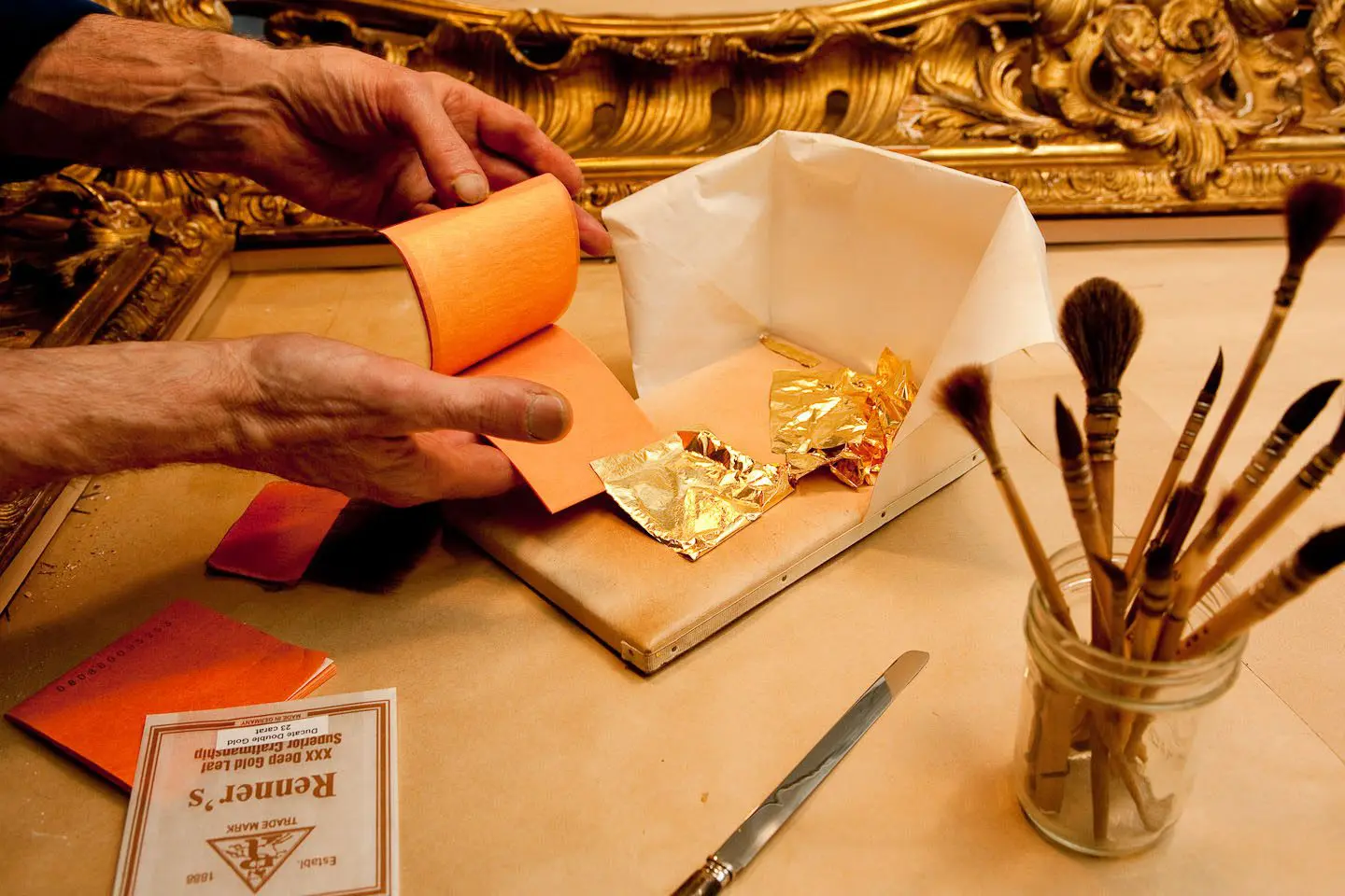 A person is cutting paper with gold leaf.