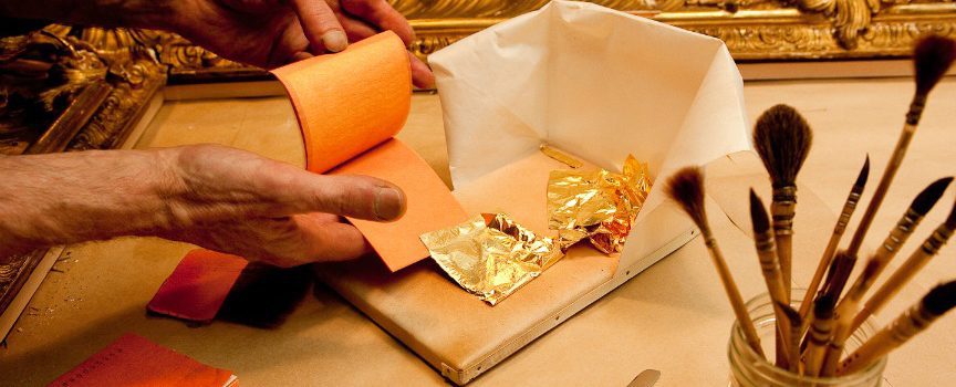 A person is wrapping gold foil onto a roll.