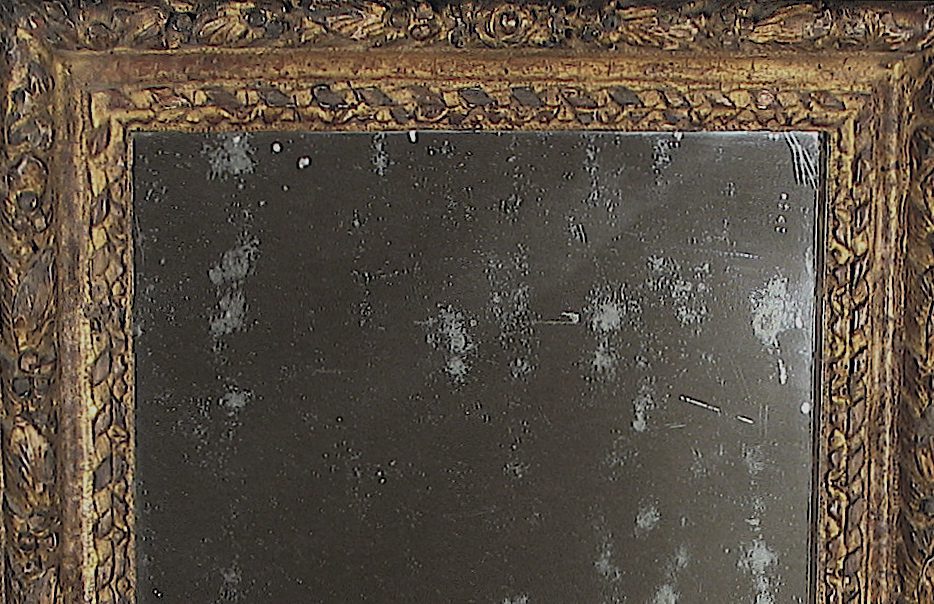 A close up of the top portion of an old mirror.