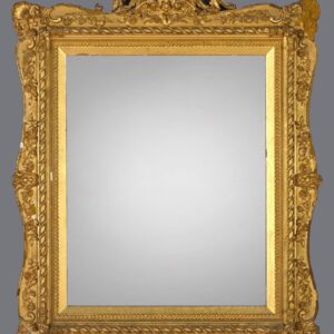 A gold framed mirror with ornate design on the top.