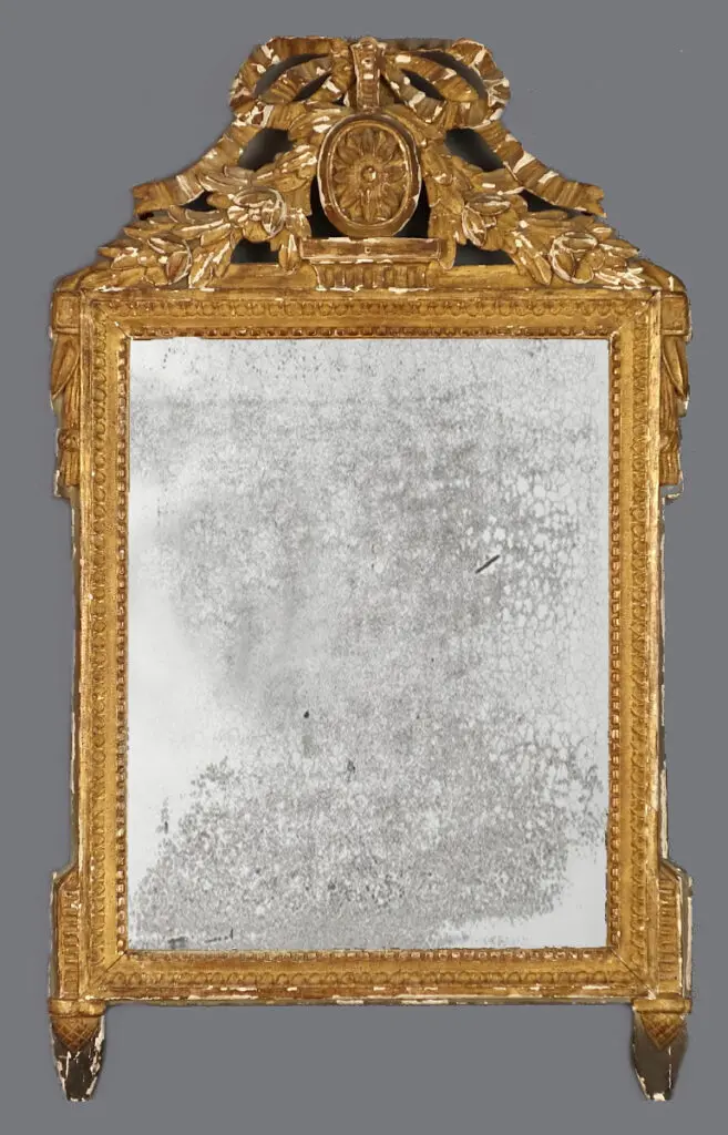 A mirror with a gold frame and a large eagle on the top.