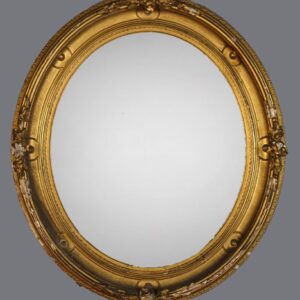 A gold oval mirror with ornate frame and gray background