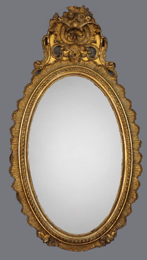 A gold mirror with an ornate frame and a gray background.