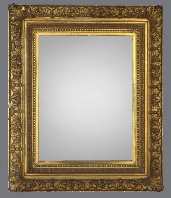 A gold frame with a mirror on the wall.