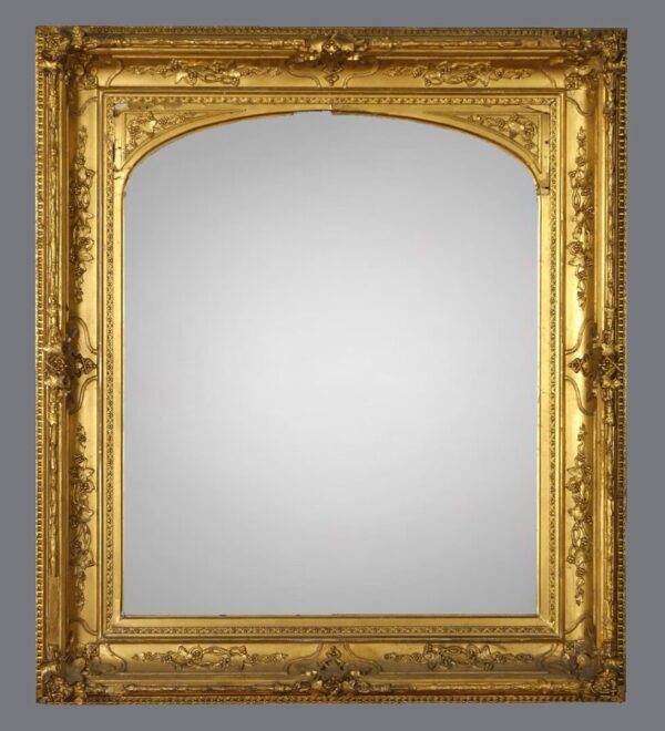 A gold frame with a mirror on the wall