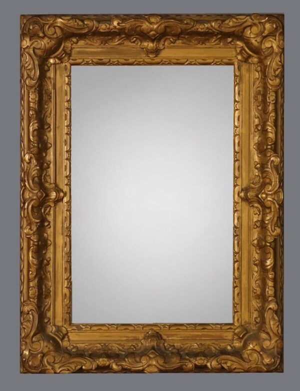 A gold framed mirror with a gray background