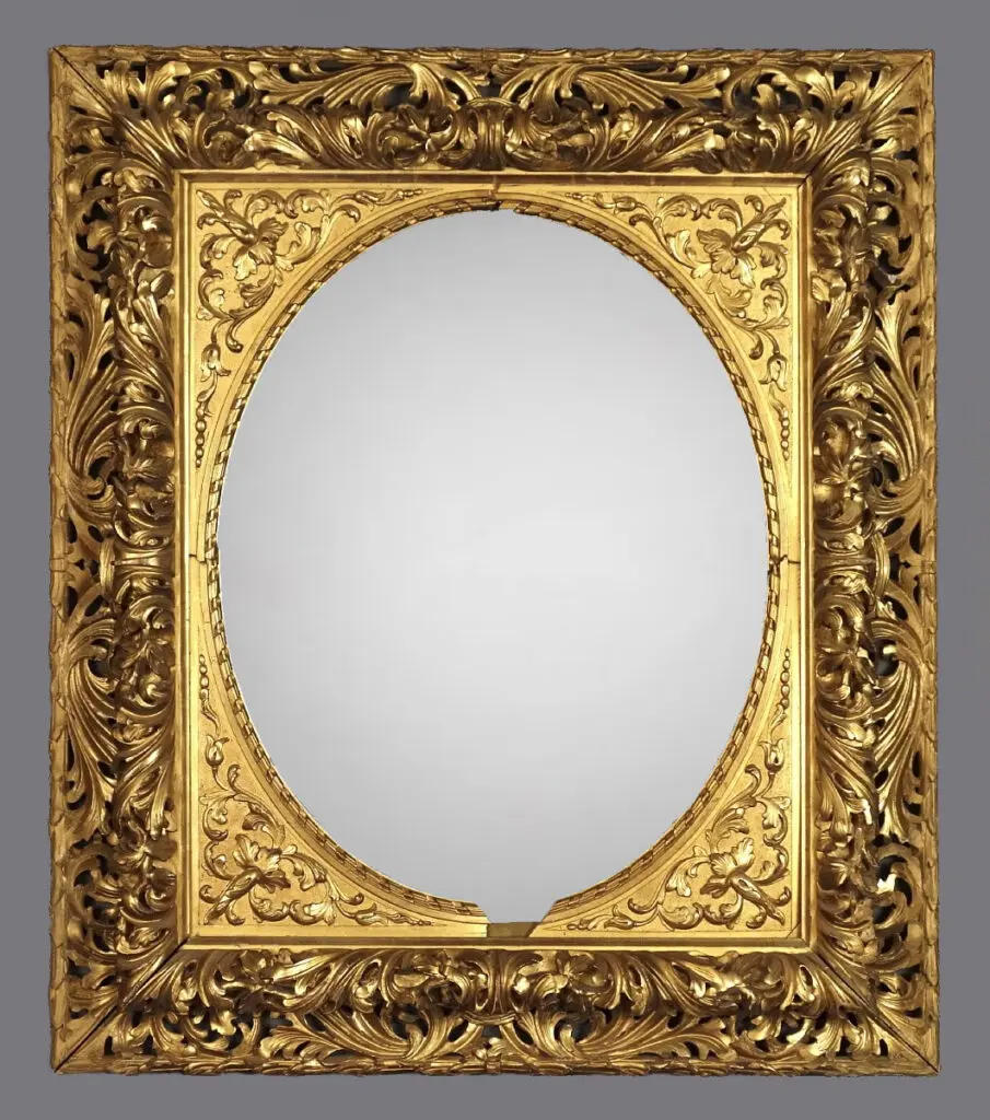 A gold frame with a mirror on the wall