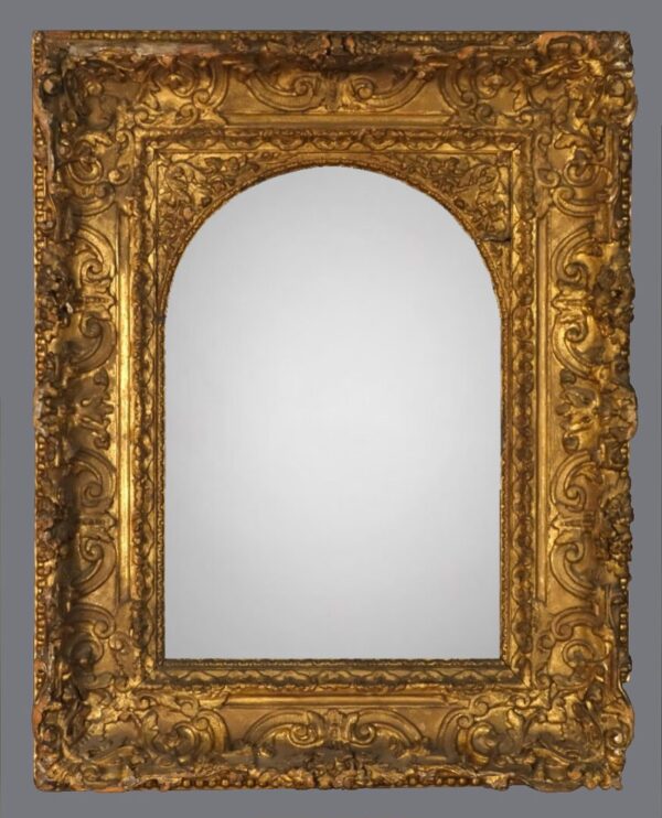 A gold frame with an arched mirror in the center.