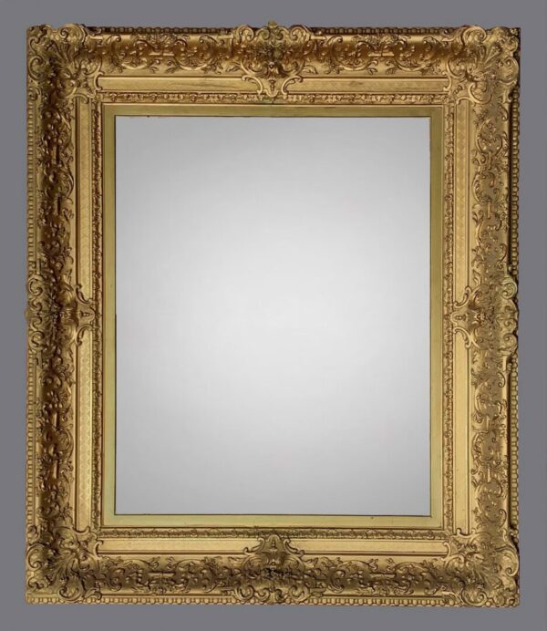 A gold frame with a mirror on the wall.