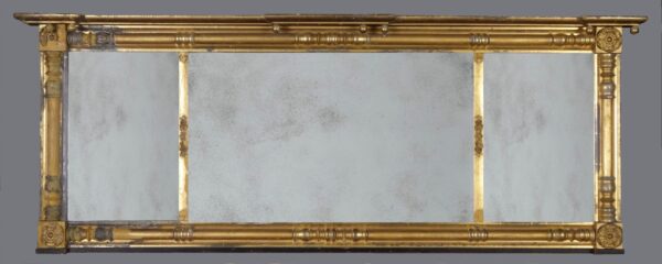 A gold framed mirror with a white background.