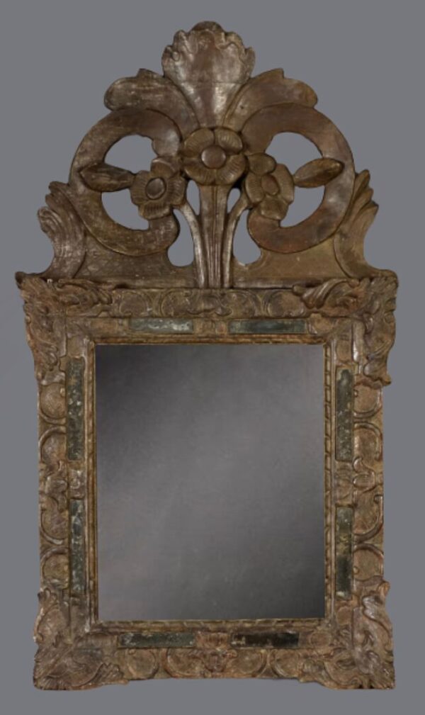 A mirror with a large carved frame and a decorative design.