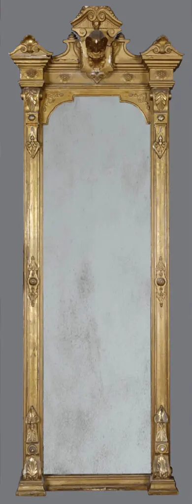 A mirror with gold frame and two small carvings.